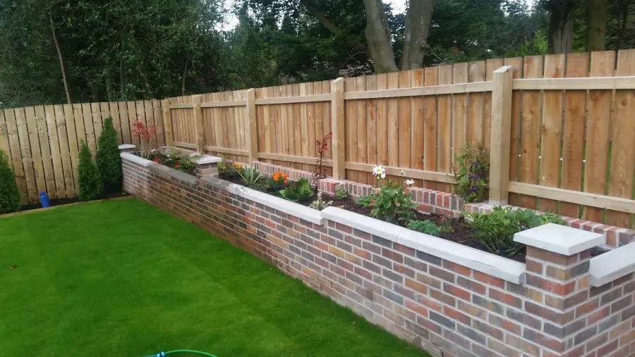 Brick wall with timber fencing and flowerbeds by Perfect Paving Belfast
