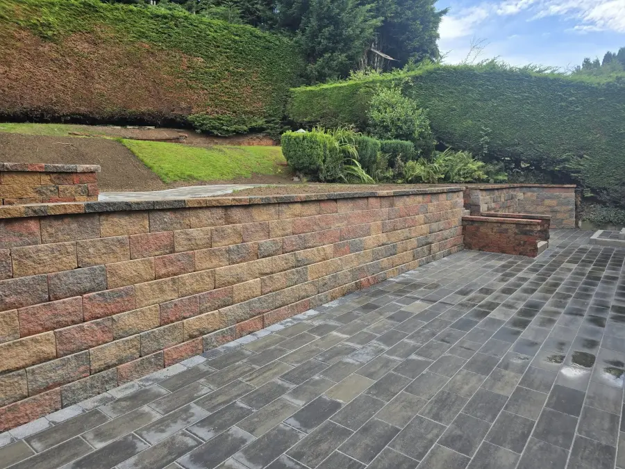Circular artificial grass feature with sandstone and stone walling by Perfect Paving Belfast